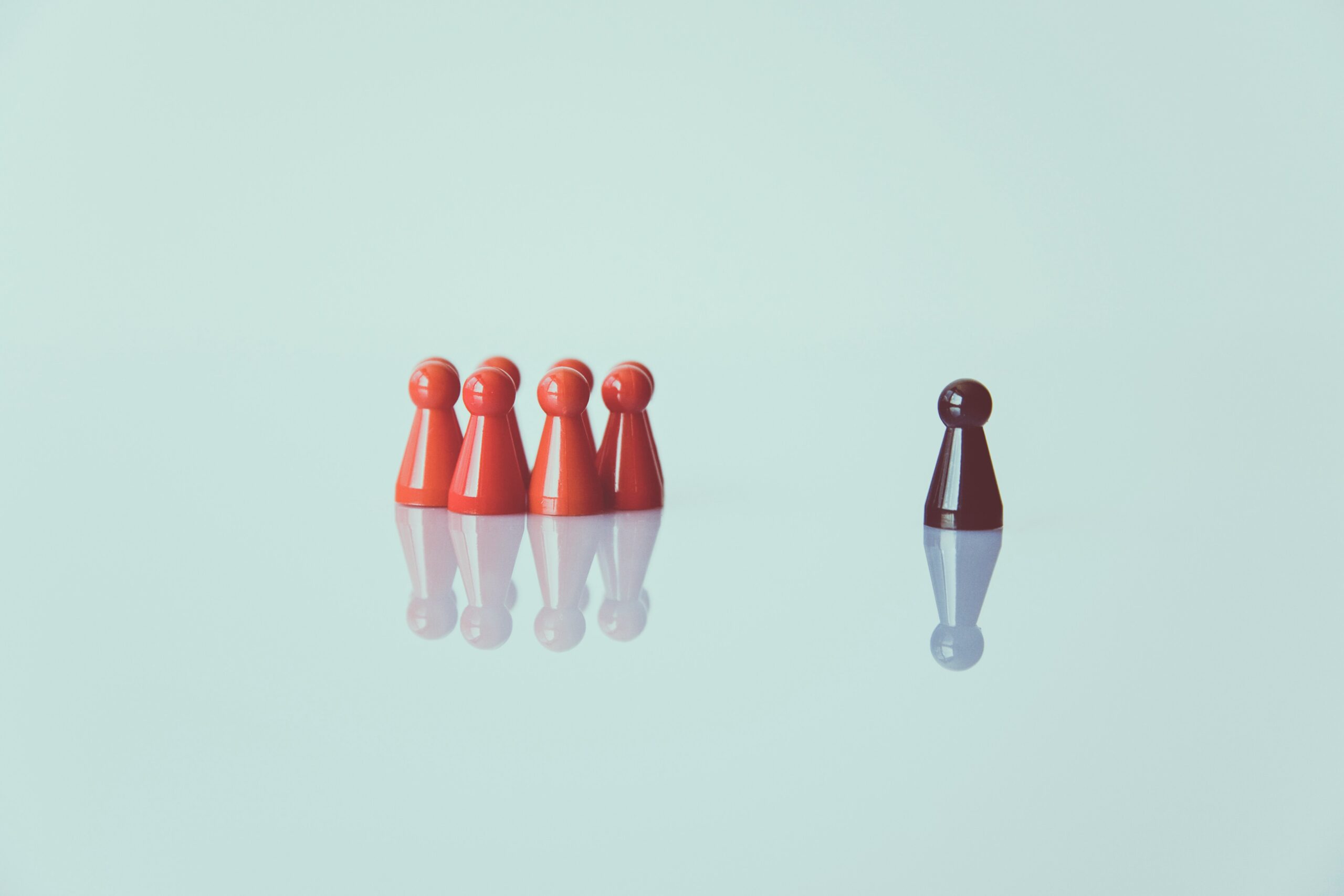 A brown figure stands apart from a group of red figures