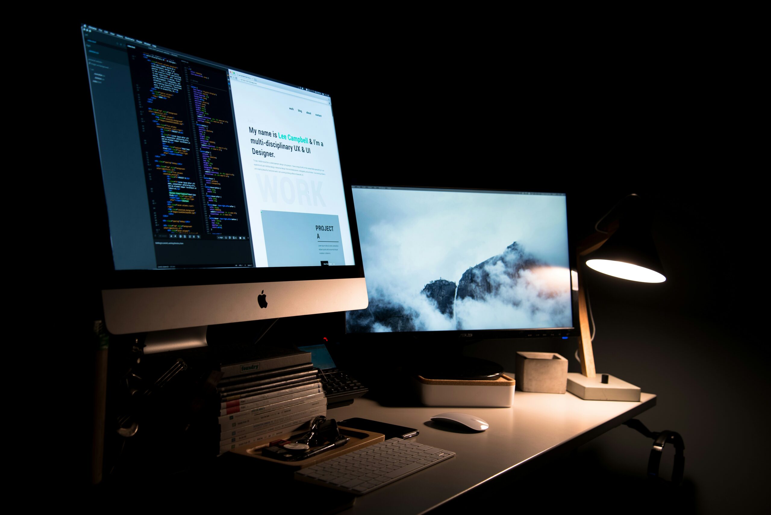 two screens on a desk with a lamp