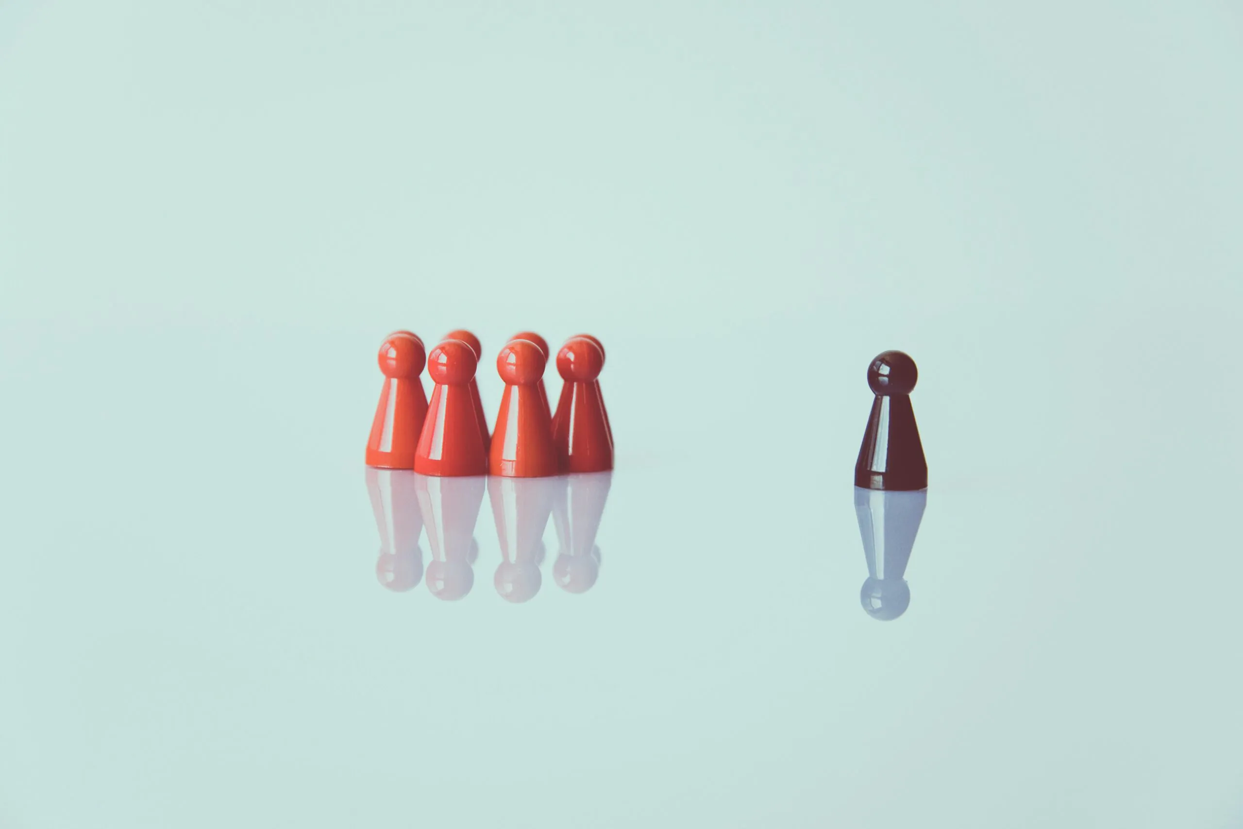 A brown figure stands apart from a group of red figures